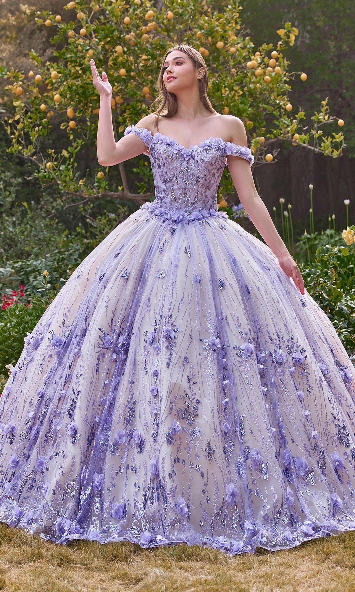Outdoors, a woman wears the Off-the-Shoulder Quince Ball Gown: Ladivine 15704 in lavender, featuring floral accents and sparkling sequins.